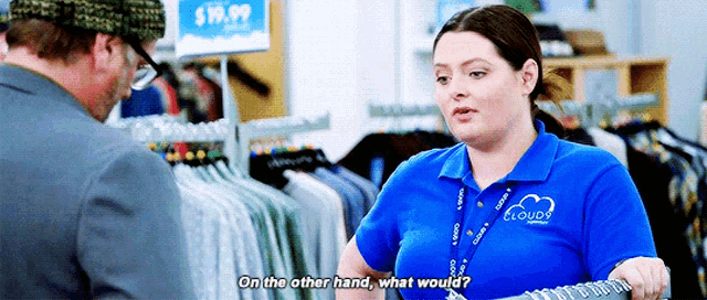 a woman in a blue shirt with the word cloudy on it is talking to a man in a suit .