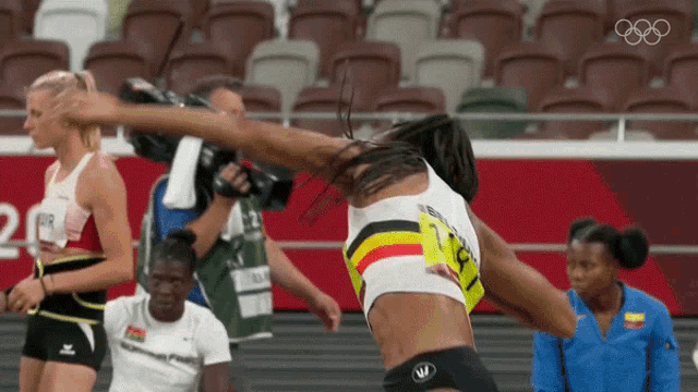 a woman is jumping in the air while a cameraman takes a picture of her in a stadium .