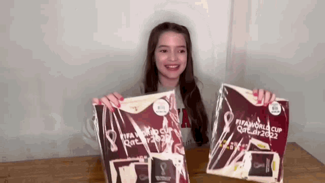 a girl is holding up a fifa world cup qatar 2022 shirt