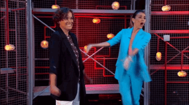 two women are standing next to each other on a stage and dancing .