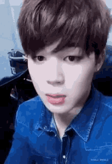 a close up of a young man wearing a blue shirt and a denim shirt .
