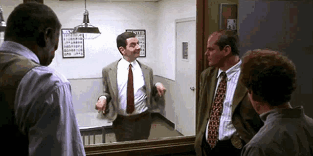 a man in a suit and tie is standing in front of a mirror talking to two other men
