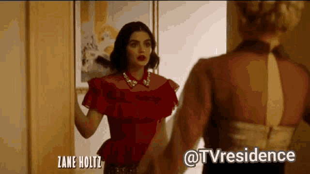 a woman in a red dress is standing next to another woman .