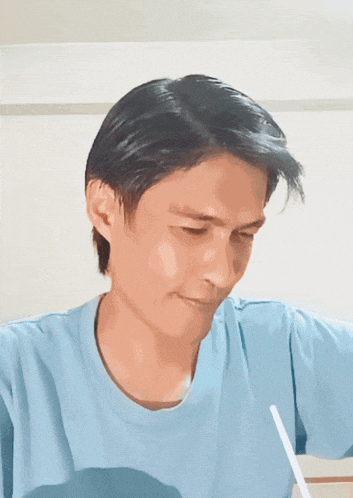 a man in a light blue shirt is looking down at something