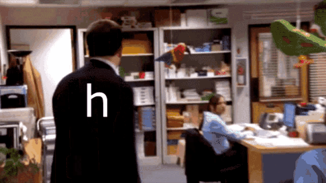 a man in a black suit with the letter h on his back