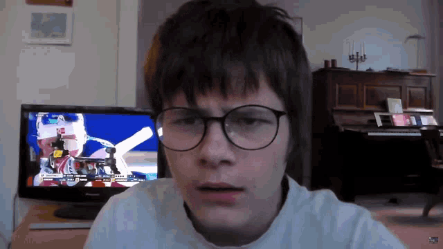 a young boy wearing glasses looks at a tv screen with a man in a ski mask on it