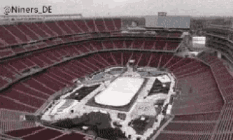 an aerial view of a stadium with empty seats and a ice rink in the middle .