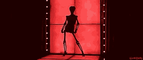 a skeleton is standing in front of a red wall in a room .