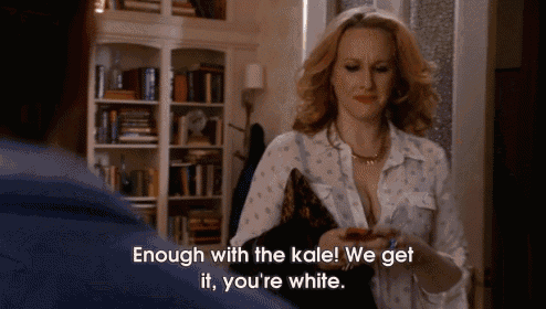 a woman is talking to a man and says " enough with the kale we get it you 're white "