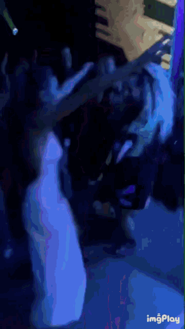 a woman in a white dress is dancing in a dark room with a blue light behind her
