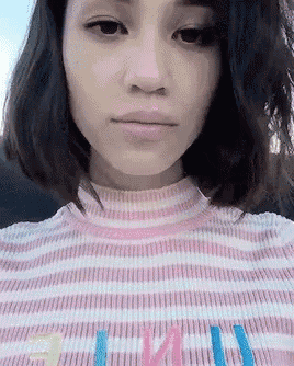 a close up of a woman wearing a pink and white striped shirt with the letter e on the front