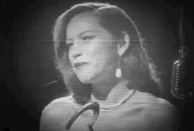 a woman singing into a microphone in a black and white photo .