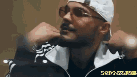 a man wearing sunglasses and a white hat has the word 50 on his sleeve