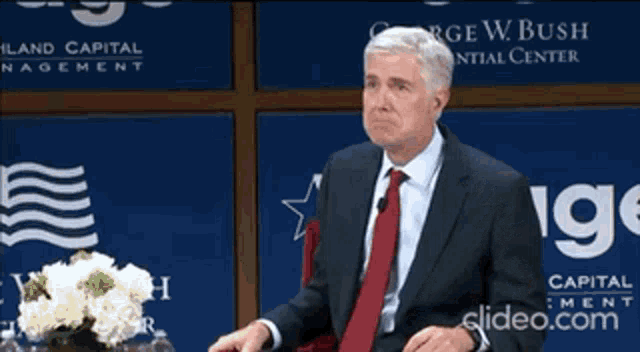 a man in a suit and tie says i 'm serious in front of george w. bush dental center