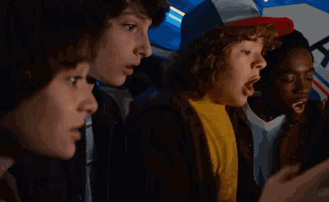 a group of young boys are looking at something with their mouth open