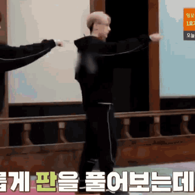 a man in a black hoodie is standing next to another man in a black hoodie while dancing .