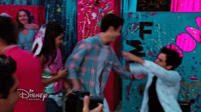 a group of people are dancing in front of a disney channel wall