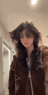 a girl is taking a selfie in front of a mirror while wearing a brown jacket with a target on it .