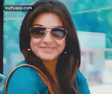 a woman wearing sunglasses is smiling and looking at the camera .