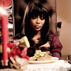 a woman is sitting in a chair at a table with a plate of food .