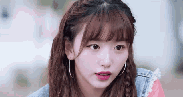 a close up of a woman wearing hoop earrings and a braided hairstyle