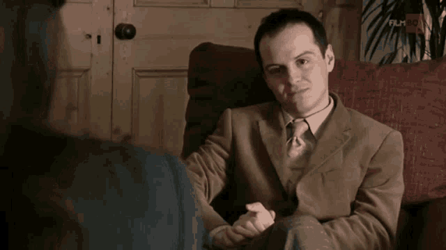 a man in a suit and tie is sitting on a couch holding a woman 's hand