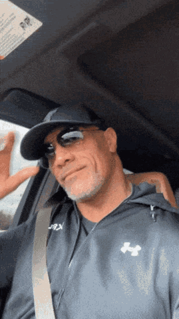 a man wearing sunglasses and an under armour jacket