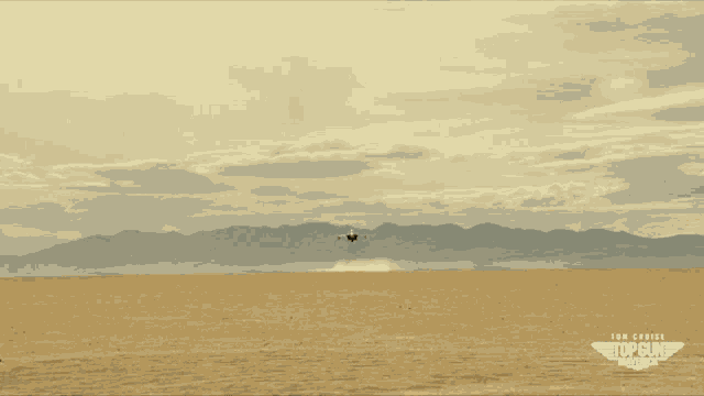 an ad for top gun maverick shows a desert landscape with mountains in the background