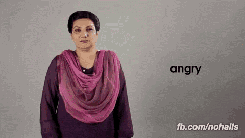 a woman wearing a purple shirt and a pink scarf is making a sign that says angry
