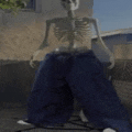 a skeleton wearing blue jeans is standing on a sidewalk in front of a building .
