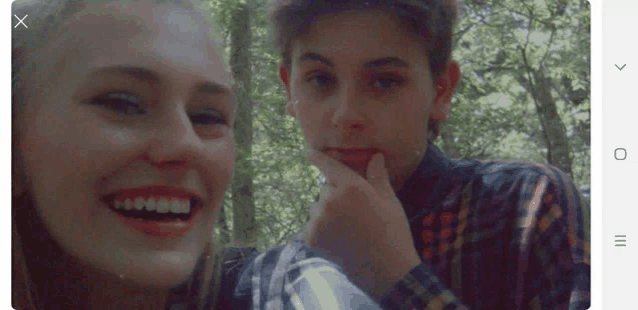 a boy and a girl are posing for a picture and the girl is smiling and the boy is covering his mouth with his hand