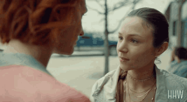 two women looking at each other with the letters hw on the bottom right