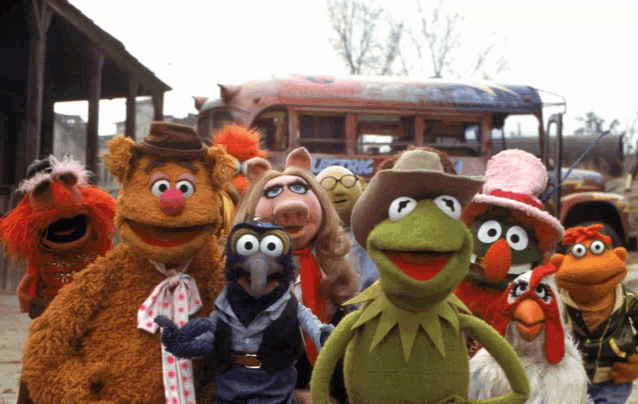 a group of muppets are posing for a picture in front of a bus that says muppets