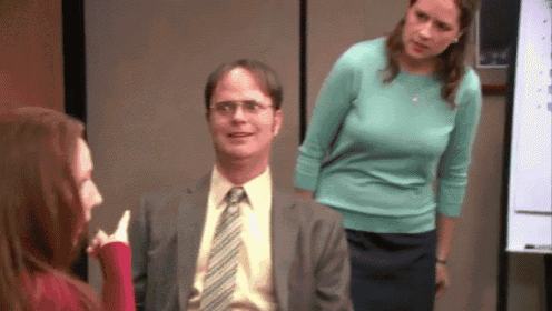 a man in a suit and tie is sitting in a chair with two women standing behind him .