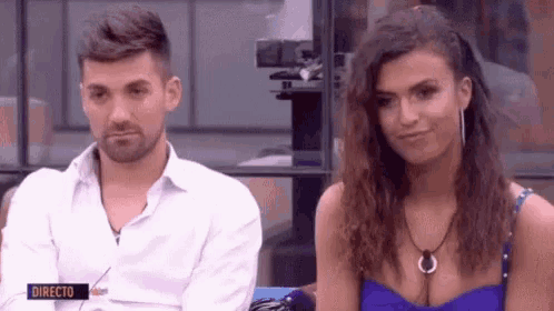 a man and a woman are sitting next to each other in front of a sign that says directo on it .
