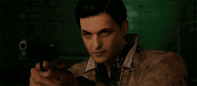 a man in a leather jacket is holding a gun in his hand .