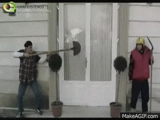 two men are standing next to each other holding shovels in front of a door .
