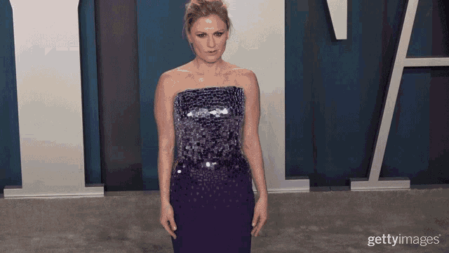 a woman in a strapless purple dress is standing in front of a sign that says ' gettyimages '