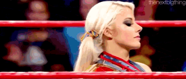 a woman is standing in a boxing ring with her head down .