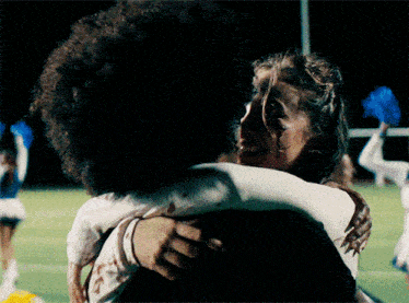 a woman with blood on her face is hugging a man with an afro