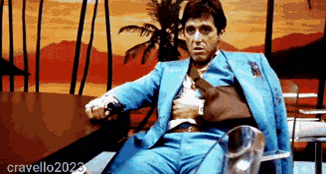 a man in a blue suit is sitting in front of a palm tree with the year cravello2023