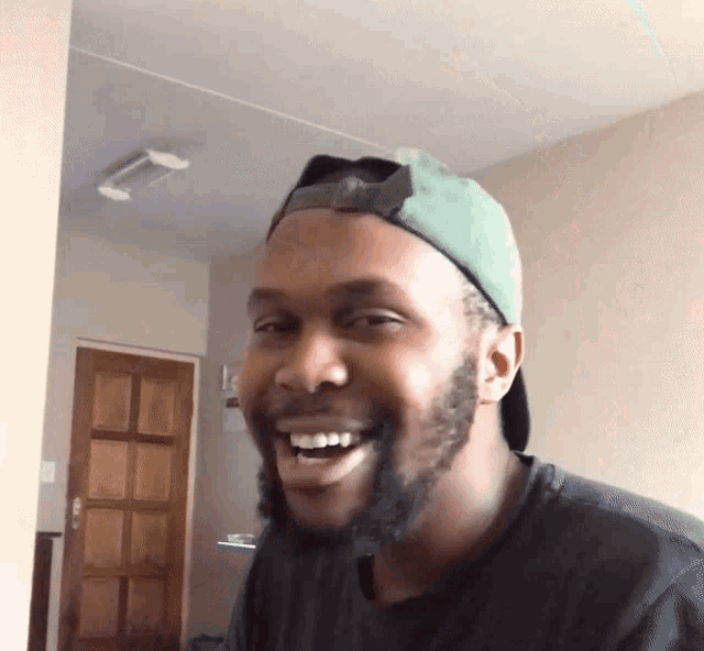 a man with a beard wearing a green hat and smiling
