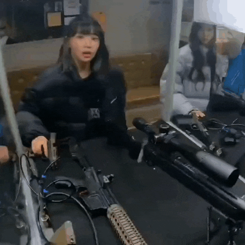 a woman is sitting at a table with a rifle and a sniper rifle .