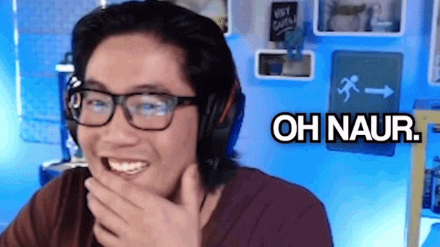 a man wearing glasses and headphones is laughing and covering his mouth with his hand with the words oh naur behind him .