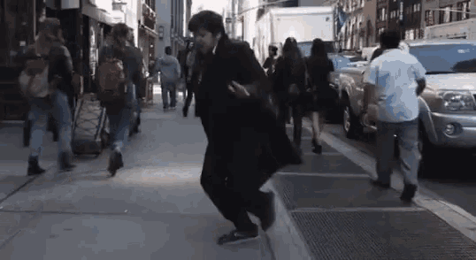 a man in a black coat is walking down a city street