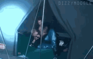 a man is sitting in a tent with dizzymoogle written on the top