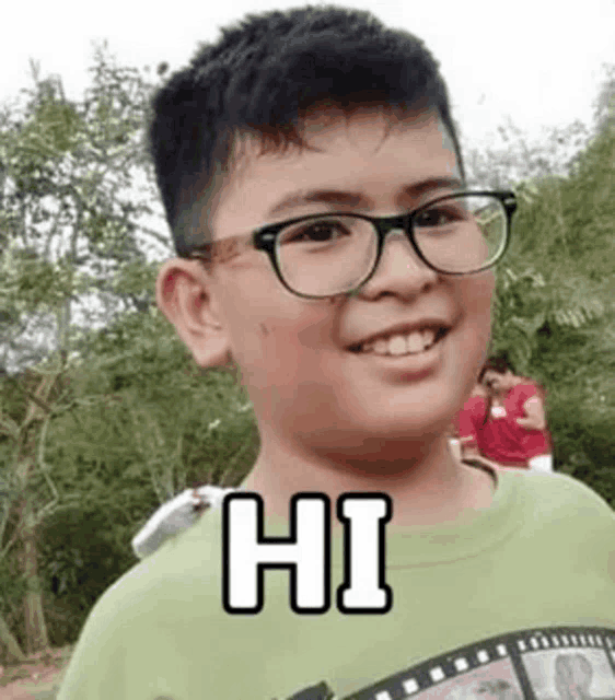 a young boy wearing glasses and a green shirt is smiling for the camera .