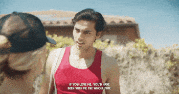 a man in a red tank top talks to a woman in a black hat