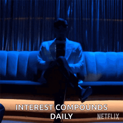 a man is sitting on a couch with interest compounds daily written on the bottom