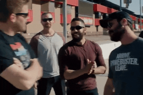 a group of men are standing next to each other and one of them is wearing a shirt that says power buster league .